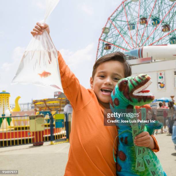 boy at amusement park with stuffed dinosaur and goldfish - goldfish stock pictures, royalty-free photos & images