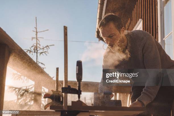 man sawing wood for home improvement carpentry outdoors in cold winter - sawing stock pictures, royalty-free photos & images