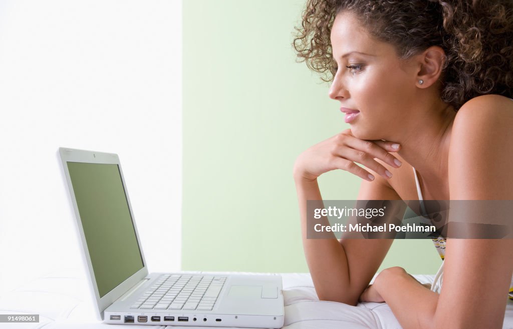 Mixed race woman laying on sofa using laptop