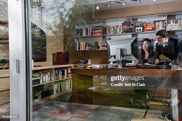 mixed race businesswoman sitting at desk with co-worker - arab businesswoman with books stock-fotos und bilder