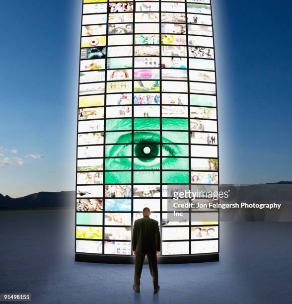 businessman standing next to pillar of television screens - advertising column - fotografias e filmes do acervo