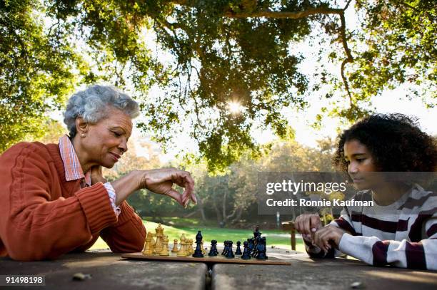 african woman playing chess with granddaughter - playing chess stockfoto's en -beelden