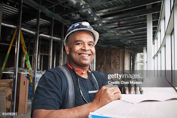 mixed race worker on construction site - hispanic construction worker stock-fotos und bilder