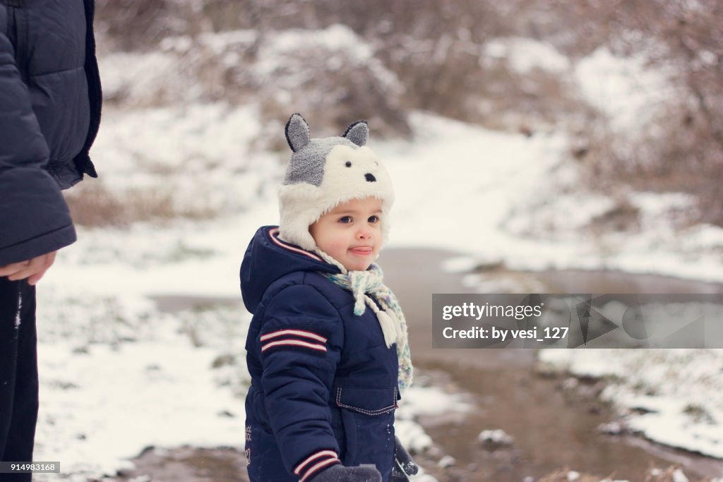 Portrait of a cute toddler wearing a raccoon hat in winter wonderland