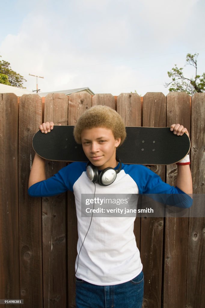 Mixed race boy in headphones holding skateboard