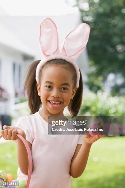 african girl wearing bunny ears and holding easter egg - easter bunny ears ストックフォトと画像