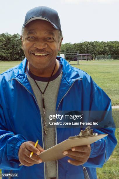 african football coach holding clipboard on field - american football coach stock-fotos und bilder