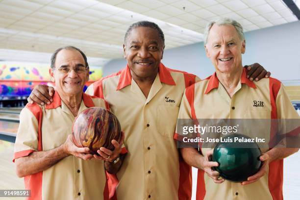 men in team uniforms holding bowling balls - man holding bowling ball stock pictures, royalty-free photos & images