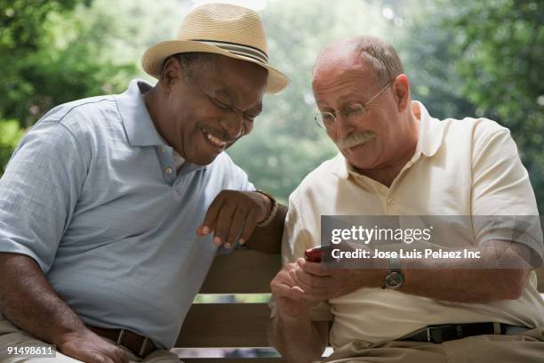 men looking at cell phone on park bench - old man laughing stock pictures, royalty-free photos & images