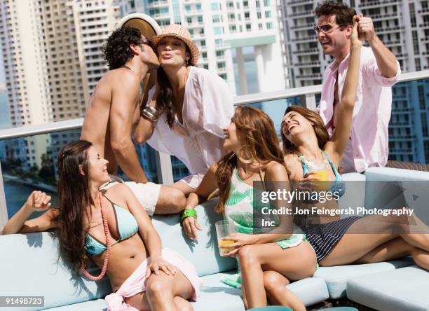 hispanic men and women partying on rooftop - chest kissing stockfoto's en -beelden