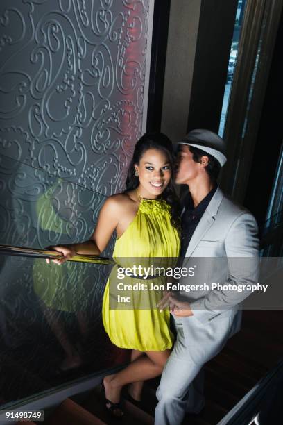man whispering in woman's ear on stairway - miami nightclub stock pictures, royalty-free photos & images
