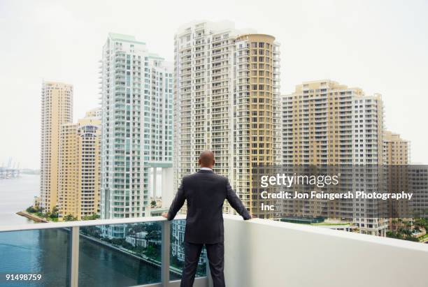 african businessman looking at city from urban balcony - miami business imagens e fotografias de stock