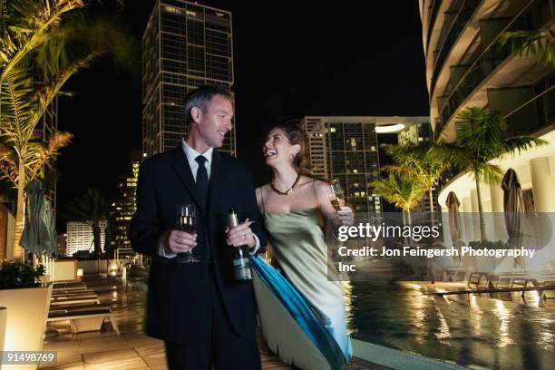 couple poolside with champagne bottle and glasses - evening wear stock pictures, royalty-free photos & images