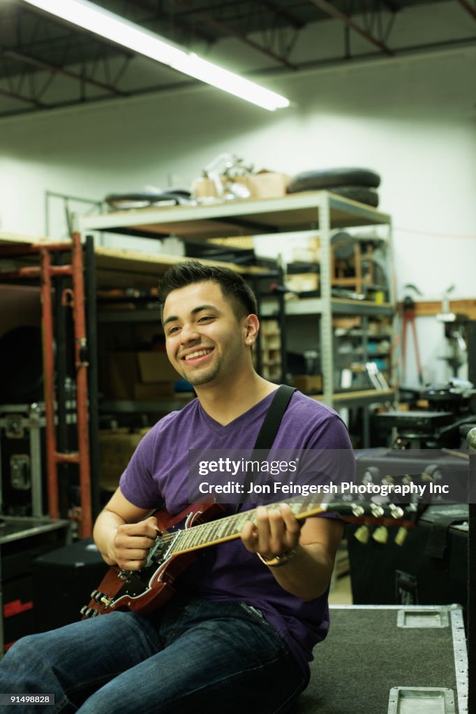 Hispanic man playing guitar in warehouse