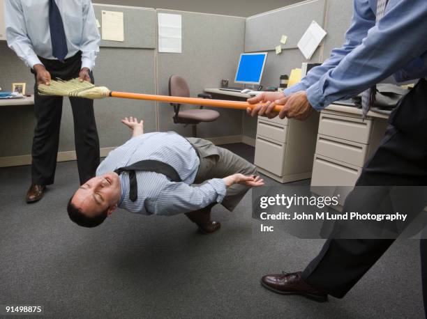 businessmen playing limbo with broom in office - limbo stock-fotos und bilder