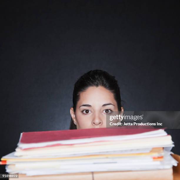 hispanic woman behind tall stack of paperwork - overdoing stock pictures, royalty-free photos & images