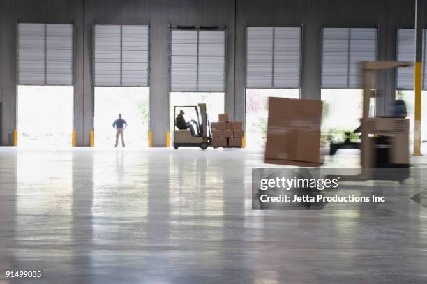 forklifts moving pallets in warehouse - gabelstapler amerika stock-fotos und bilder