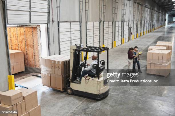 forklift moving boxes onto truck at loading dock of warehouse - muelle de carga fotografías e imágenes de stock
