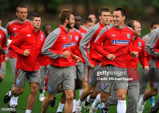 Captain John Terry and David Beckham share a joke as the warm up during the England training session at London Colney on October 6, 2009 in St...