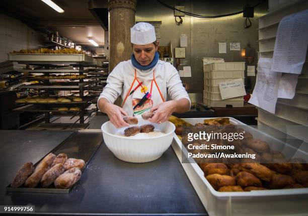 Pastry chef puts the sugar on Frittelle, a typical sweet of Venetian carnival, in Rosa Salva laboratory on February 6, 2018 in Venice, Italy. Galani,...