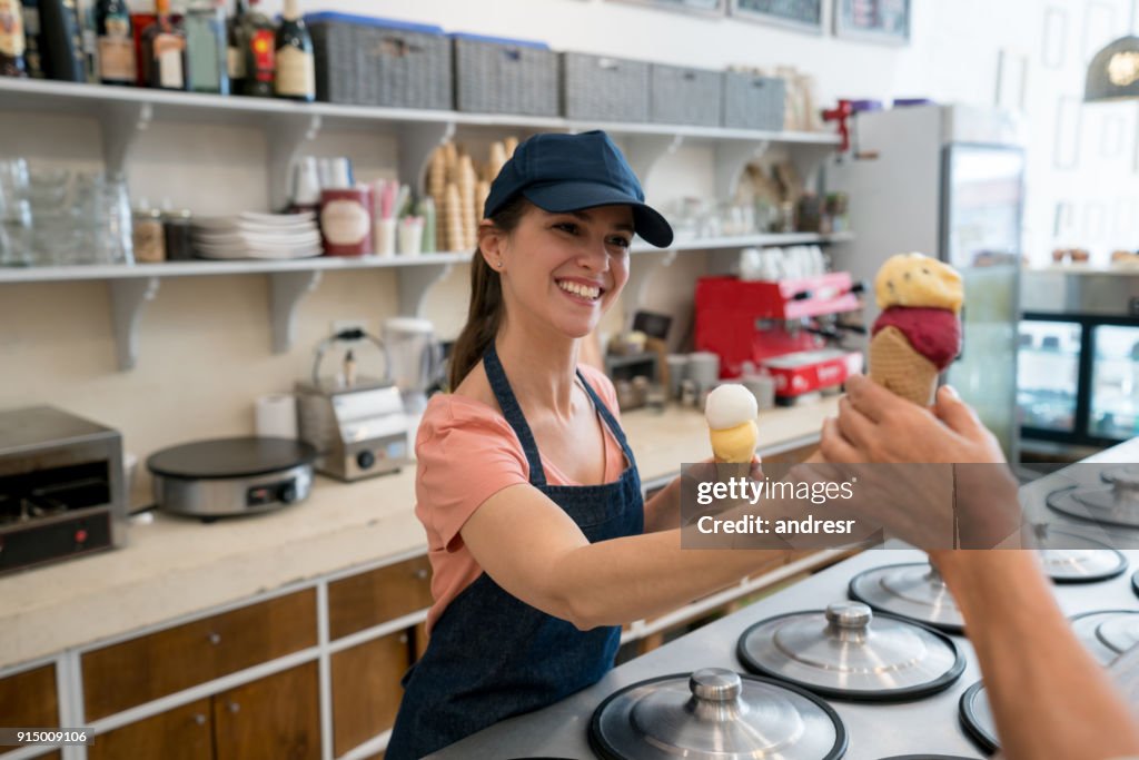 Trabajadora, sirviendo un helado a un cliente irreconocible en la heladería
