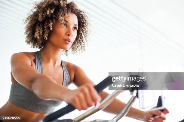 vrouw doen cardio oefeningen op een upright bike in de sportschool - woman twirling stockfoto's en -beelden