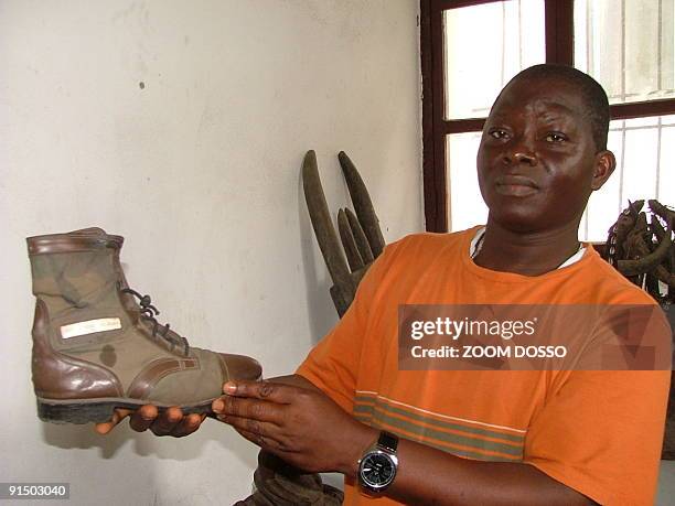 Albert Mackeh, the administrator of the National Museum of Liberia holds up the shoe of Prince Johnson, the warlord who ordered the killing of former...