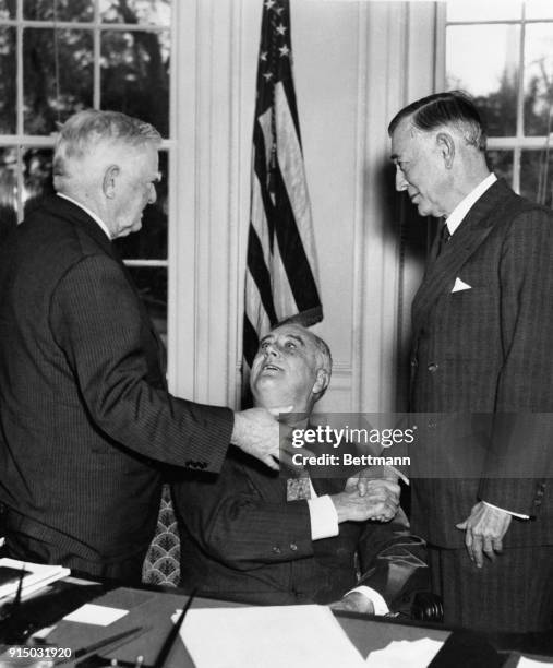 President Roosevelt listening to the gesture-accompanied conversation of Vice President Garner while shaking hands with Senator Key Pittman, Chairman...