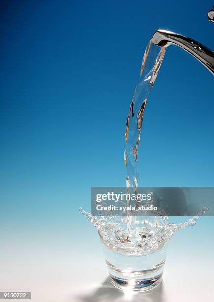 spritzendes wasser in ein glas wasser - wasser ressource stock-fotos und bilder