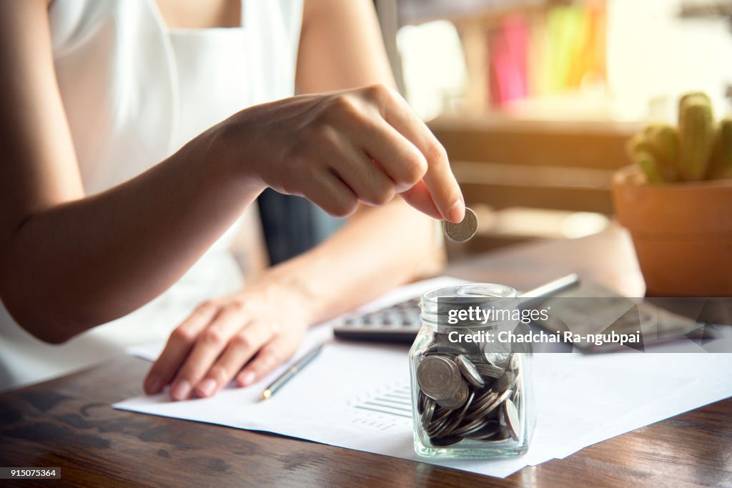 Hand of female putting coin in jar with money stack step growing growth saving money, Concept finance business investment