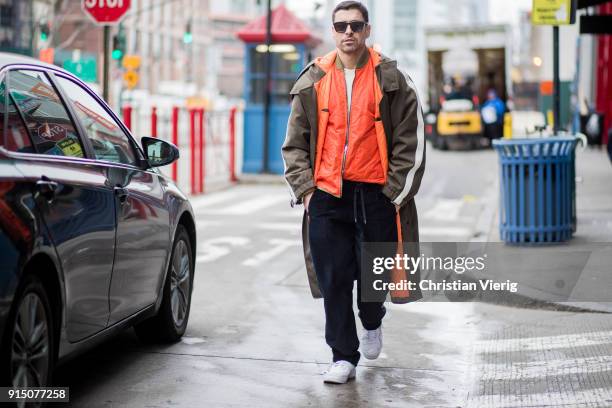 Alex Badia wearing coat, orange jacket, navy pants, white sneakers seen during Mens' New York Fashion Week on February 6, 2018 in New York City.