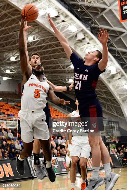 Amir Bell of the Princeton Tigers drives to the basket against Ryan Betley and Max Rothschild of the Pennsylvania Quakers during the first half at L....