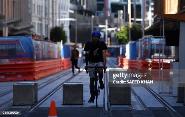 Man rides his bicycle over newly laid light train tracks on George Street in the central business ditrict of Sydney on February 7, 2018. The...