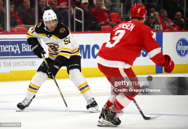 Ryan Spooner of the Boston Bruins makes a pass behind Nick Jensen of the Detroit Red Wings during the first period at Little Caesars Arena on...