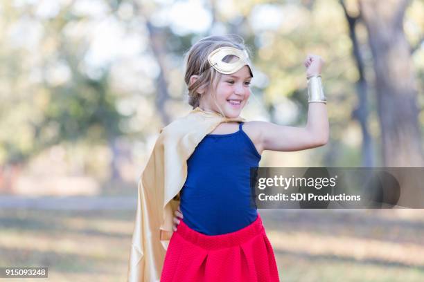 little girl superhero showing her muscles while playing outside - heroes 2017 show stock pictures, royalty-free photos & images