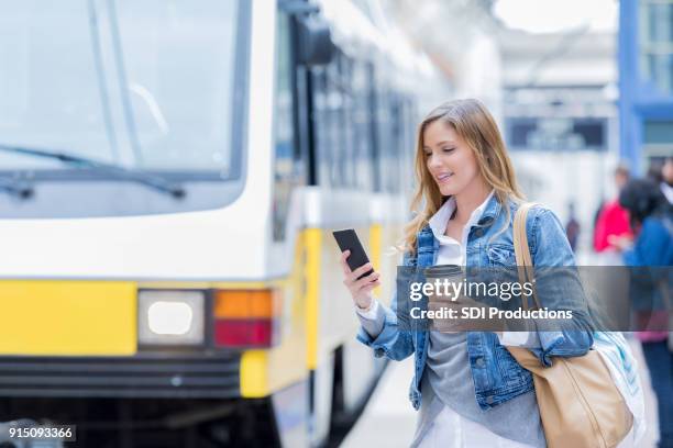 woman texts on smart phone before boarding commuter train - texas independence stock pictures, royalty-free photos & images