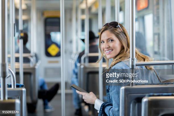 woman looks back at camera on commuter train - airport bus stock pictures, royalty-free photos & images