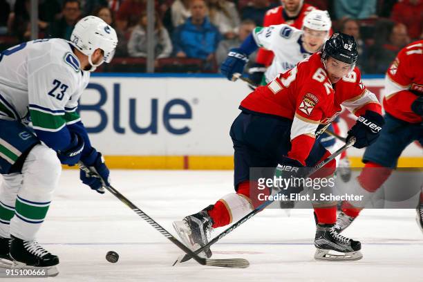 Denis Malgin of the Florida Panthers crosses sticks with Alexander Edler of the Vancouver Canucks at the BB&T Center on February 6, 2018 in Sunrise,...