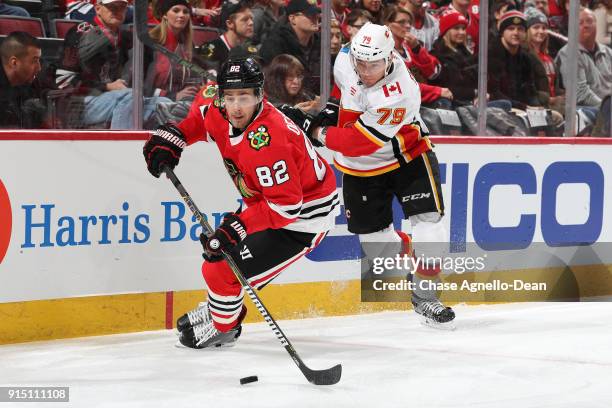 Jordan Oesterle of the Chicago Blackhawks and Micheal Ferland of the Calgary Flames chase the puck in the first period at the United Center on...