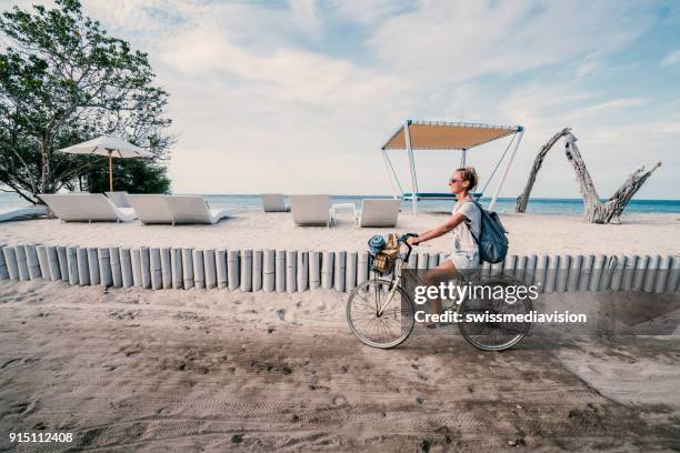 meisje fietsten aan het strand in de ochtend, indonesië - gili trawangan stockfoto's en -beelden