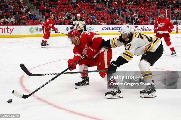 Nick Jensen of the Detroit Red Wings tries to get control of the puck in front of Austin Czarnik of the Boston Bruins during the third period at...