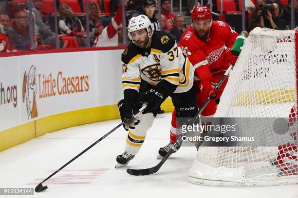 Patrice Bergeron of the Boston Bruins tries to get around the stick of Luke Glendening of the Detroit Red Wings during the third period at Little...