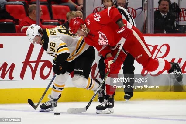 Martin Frk of the Detroit Red Wings tries tries to get control of the puck next to David Pastrnak of the Boston Bruins during the third period at...