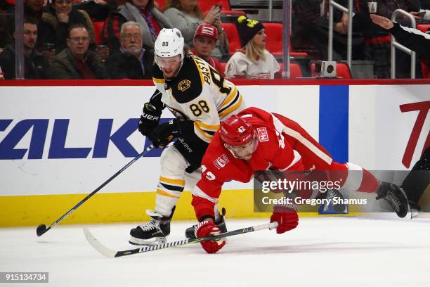 Martin Frk of the Detroit Red Wings losses his footing next to David Pastrnak of the Boston Bruins during the third period at Little Caesars Arena on...