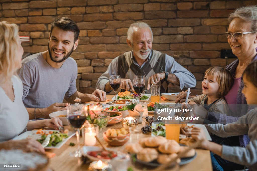 Happy extended family communicating while having a dinner at dining table.