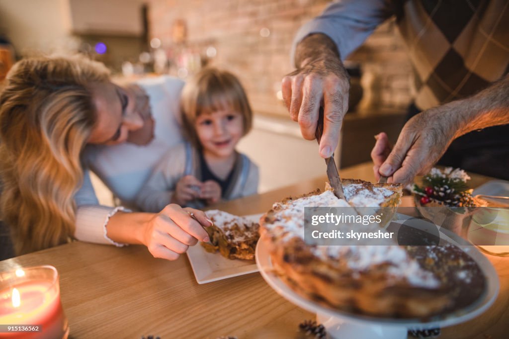 Close up of unrecognizable man cutting apple pie during meal with his family.
