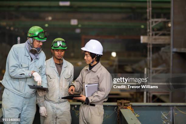 three workers meeting and talking in an industrial setting - 工場　日本人 ストックフォトと画像