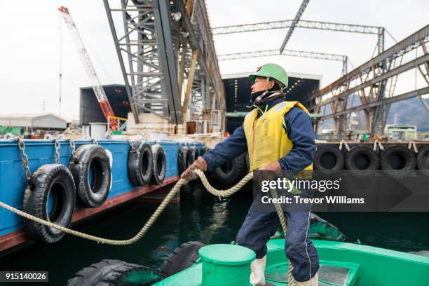 a deckhand on a tugboat at a commercial dock - tug boat stock-fotos und bilder