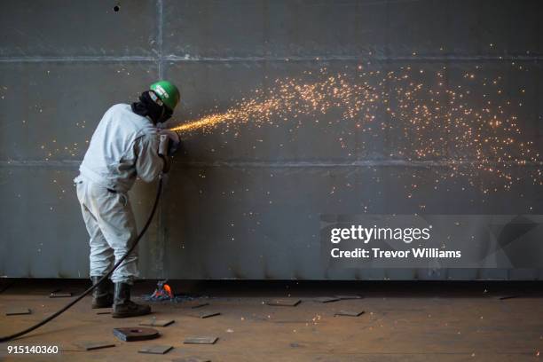 an iron worker grinding large ship parts with sparks flying - shipbuilder stock pictures, royalty-free photos & images
