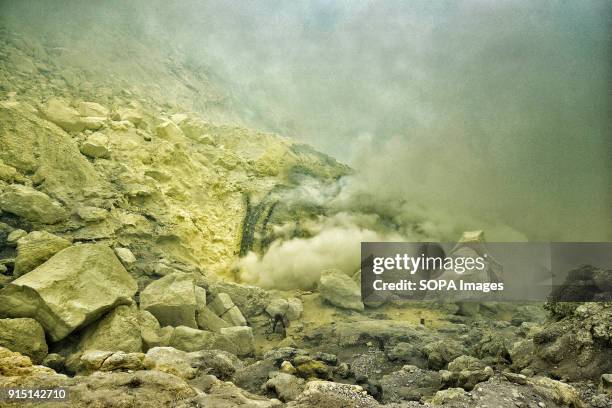 Miner extracting sulfur among the toxic gases. More than 200 men, using damp cloths as masks and an iron rod as their only tool, extract sulfur from...